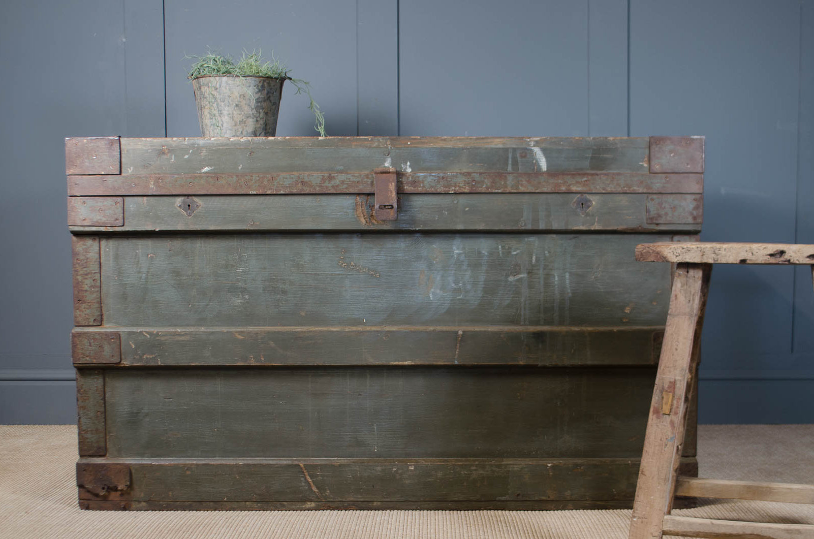 
Vintage wooden crate with a plant on top against a blue wall.
