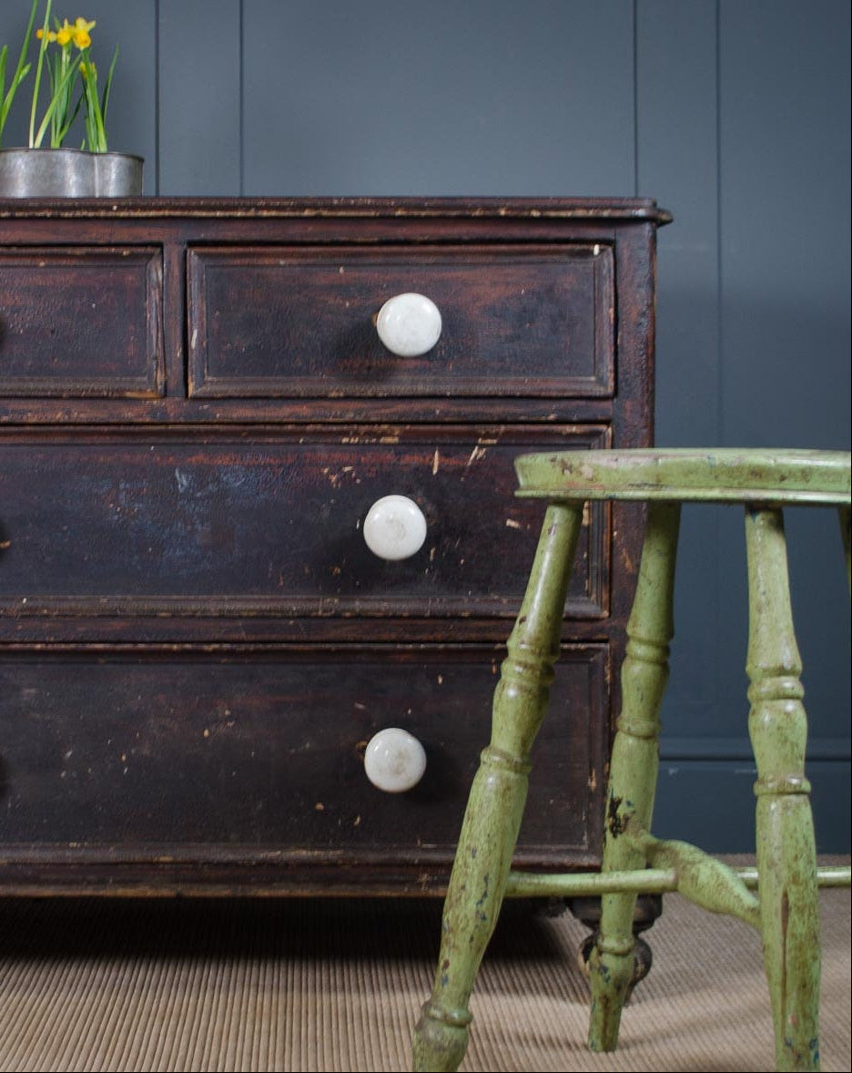 Front view of Victorian chest of drawers with four drawers, white porcelain handles, distressed scumble glaze surface, and turned feet