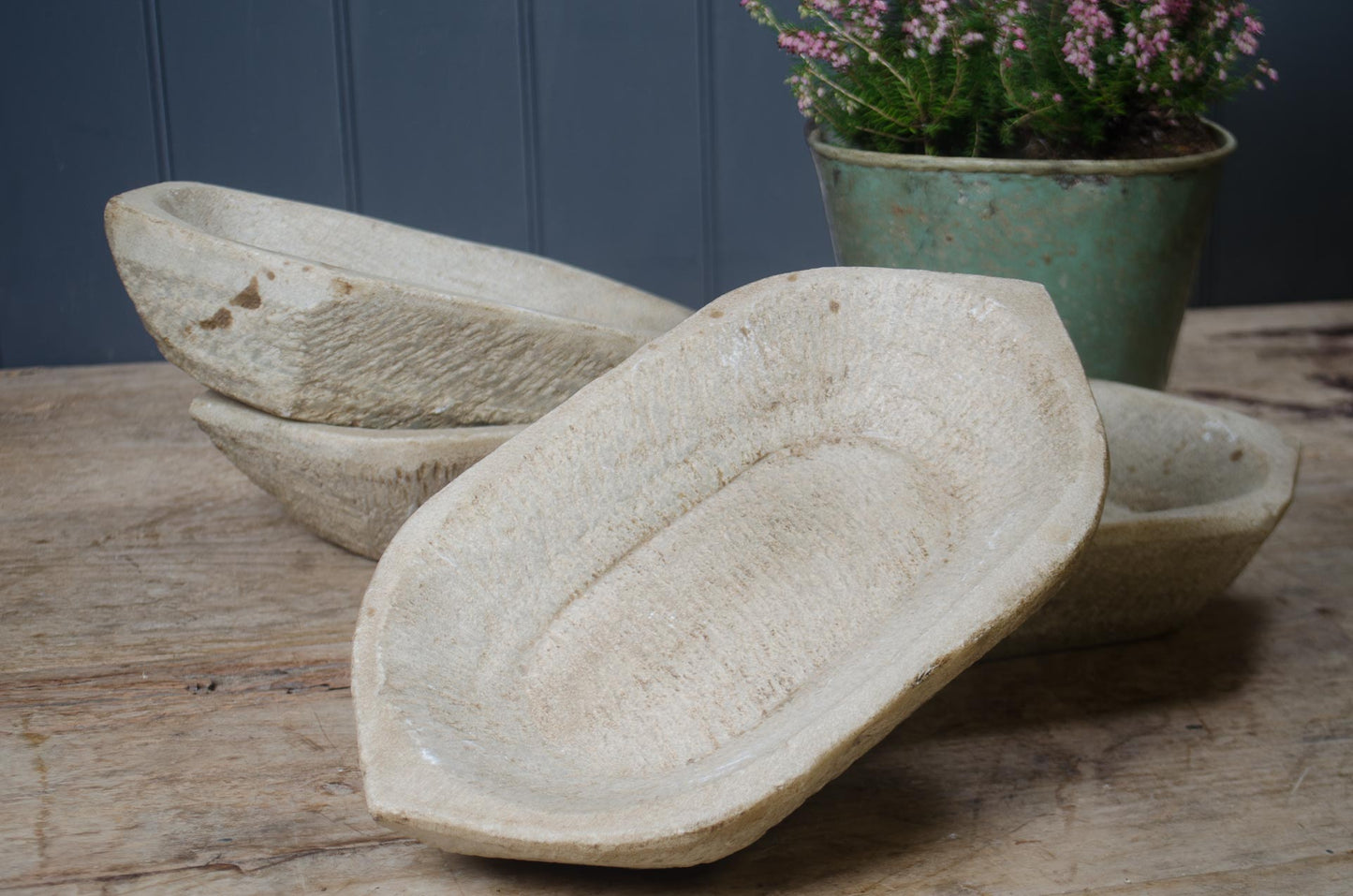 Three stone indian spice bowls on a wooden surface with a plant in the background.