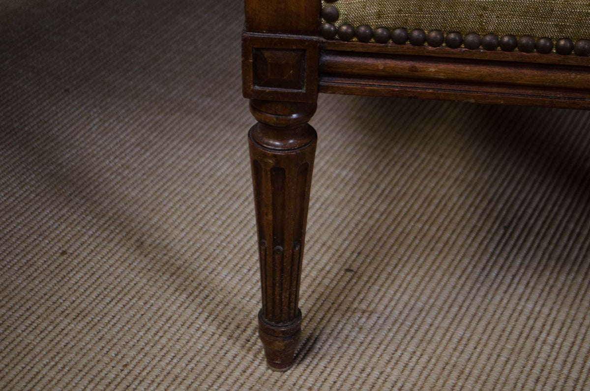 Close-up of a dark brown wooden chair leg with carved detailing, resting on a textured beige rug.
