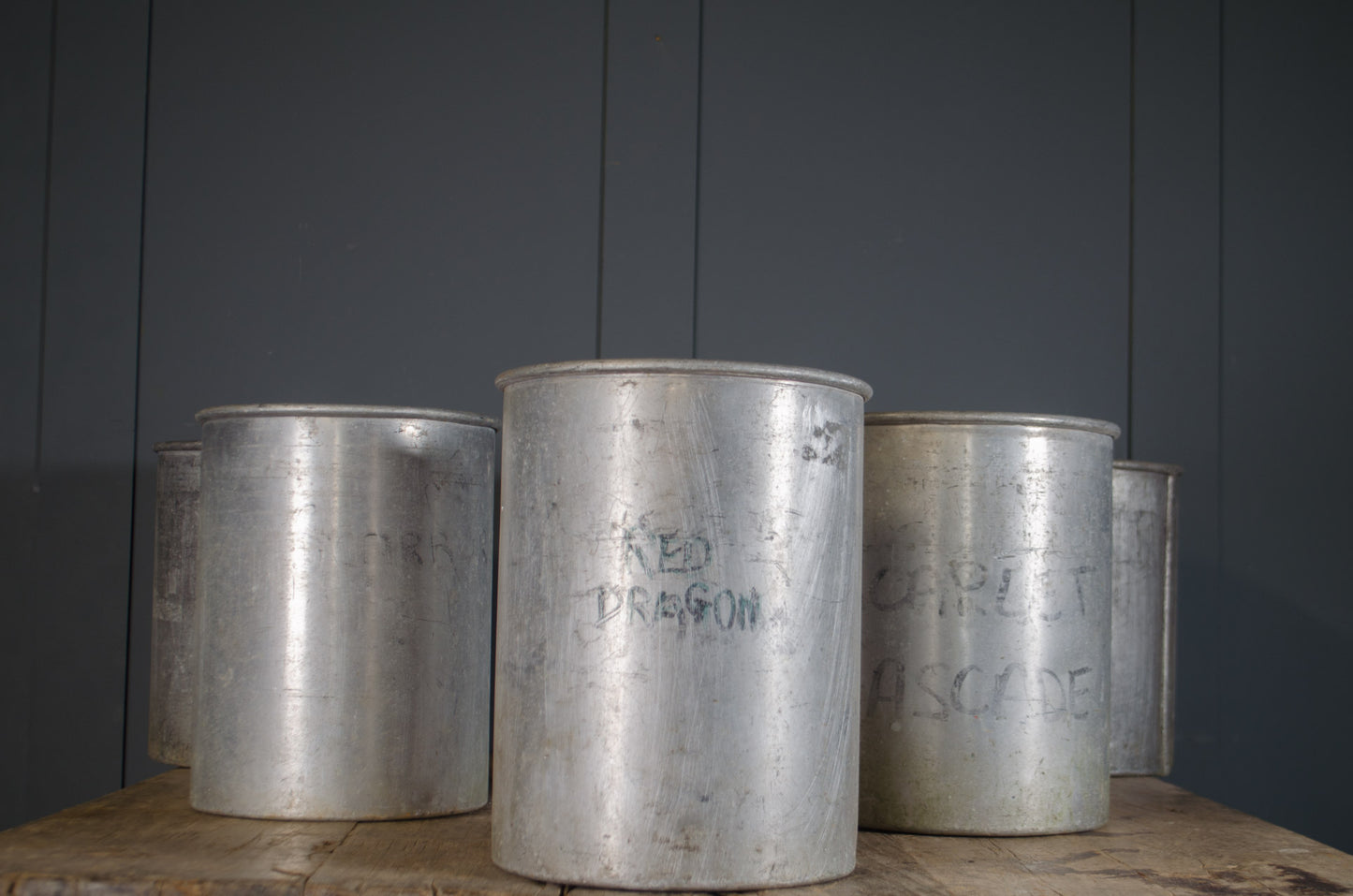 Collection of old firework canisters used as planters with herbs, showing aged metal finish and cylindrical form