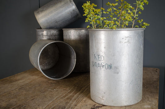 Vintage metal firework canisters with worn surface and faded original lettering displayed on wooden table