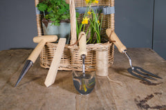 Set of gardening tools with wooden handles including trowel, fork, dibber, plant label and twine laid out on wooden surface