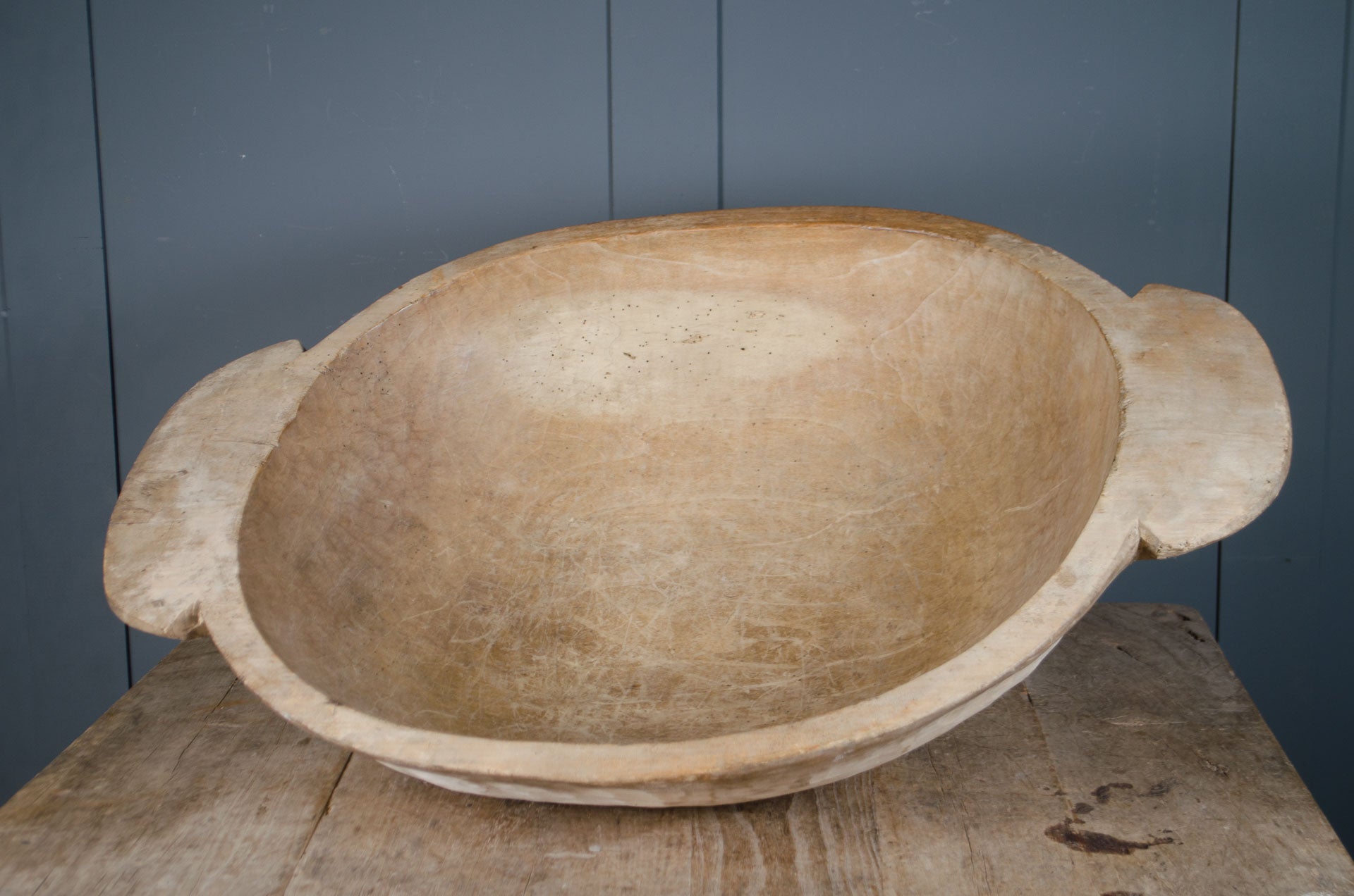 Pair of antique wooden dough bowls with carved handles, pale waxed surface and rustic texture displayed on table
