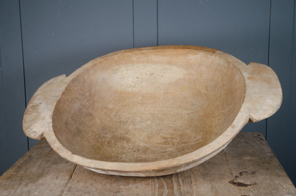 Pair of antique wooden dough bowls with carved handles, pale waxed surface and rustic texture displayed on table