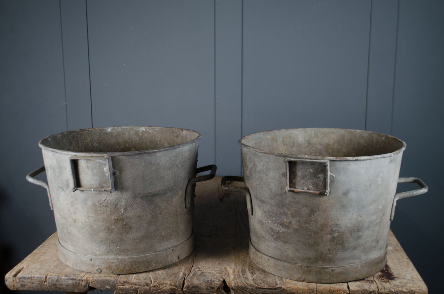 Antique zinc buckets shown as planters with drainage holes and weathered interior surface