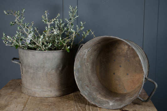 Antique zinc buckets shown as planters with drainage holes and weathered interior surface