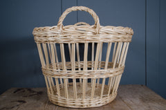 Wicker basket with handle on a wooden surface against a blue wall