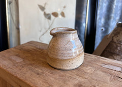 Ceramic pitcher on a wooden surface with a neutral background