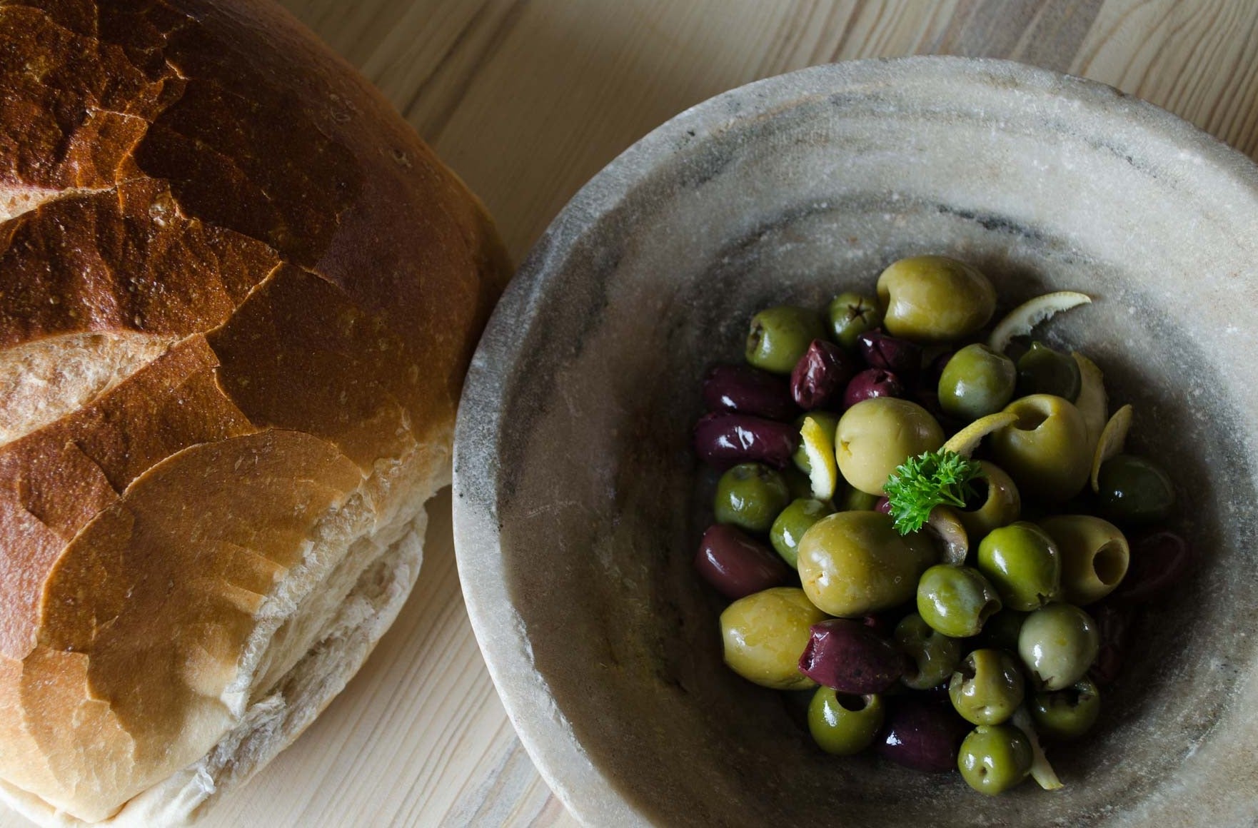 
olives in rustic  stone bowl with sourdough artisan bread